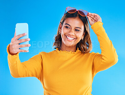 Buy stock photo Woman, face and smile in studio for selfie, social media or vlog in happiness and style against a blue background. Happy isolated female influencer smiling for picture photo, memory or online post