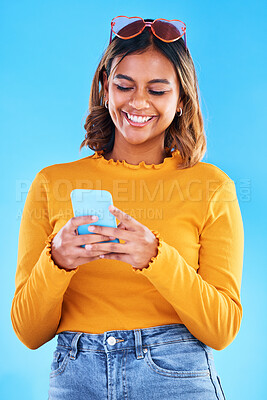 Buy stock photo Woman, phone and smile for social media, communication or chatting isolated against a blue studio background. Happy female smiling with teeth texting on mobile smartphone in happiness for online chat