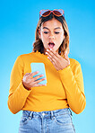 Notification, shocked and woman surprised by phone due to trending social media news isolated in a studio blue background. Wow, omg and young female amazed by a cellphone using internet or online