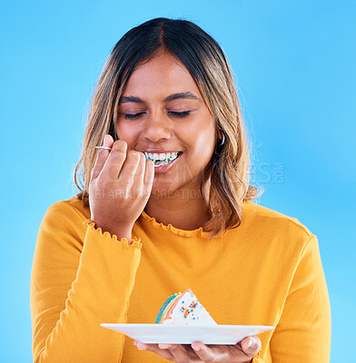 Buy stock photo Birthday, blue background and a woman eating cake in studio while having fun at a party for celebration. Dessert, food and fork with an attractive young female enjoying a rainbow pastry snack