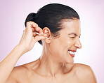 Woman, cotton bud and ear in studio for cleaning, struggle or pain for wellness by pink background. Model hand, self care or clean for hygiene, ears or natural product for healthy hearing by backdrop