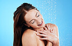 Shower, water and happy woman in studio, blue background and cleaning for hygiene. Female model washing with wet drops for beauty, skincare and grooming for self care, happiness and wellness routine 