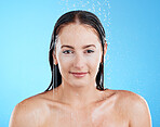 Shower portrait, water and woman in a studio with a smile from cleaning and skincare. Wellness, bathroom and beauty routine of a female model relax from dermatology and self care with blue background