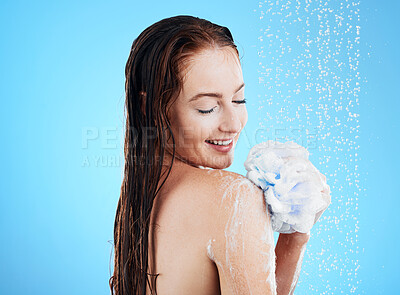 Buy stock photo Woman in shower, happy with loofah and soap, hygiene and water drops with skincare on blue background. Washing, grooming and cosmetic care with female cleaning body, foam and mockup space in studio