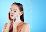 Woman face wash, shower water and studio with a young female doing skincare and beauty routine. Bathroom, dermatology and facial treatment of a model with mock up and isolated blue background