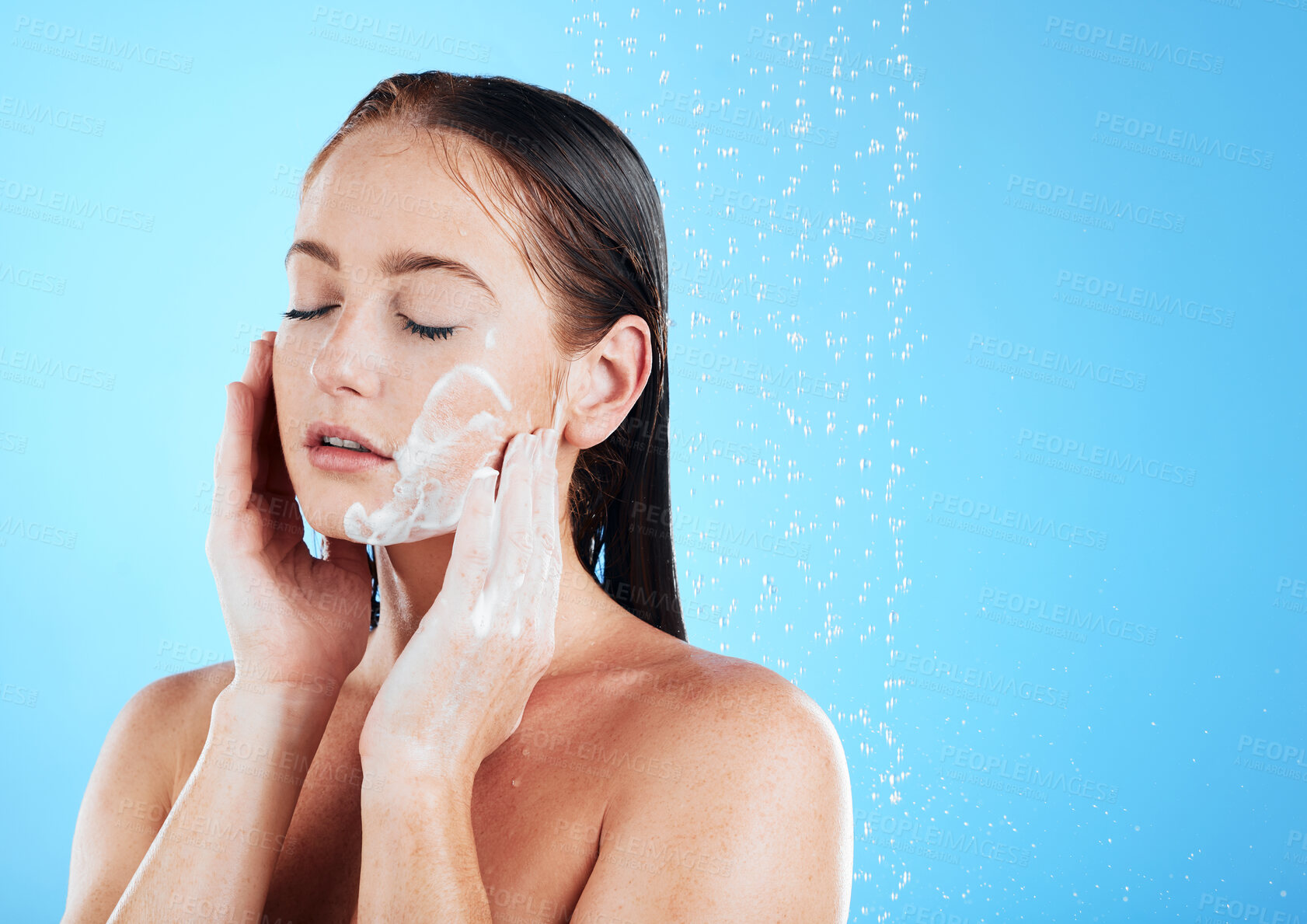 Buy stock photo Woman face wash, shower water and studio with a young female doing skincare and beauty routine. Bathroom, dermatology and facial treatment of a model with mock up and isolated blue background