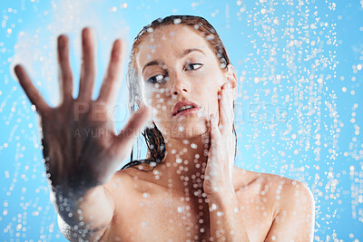 Buy stock photo Shower, water drops and woman hand doing skin cleaning, wellness and beauty routine in bathroom. Isolated, blue background and studio with a young female doing hair care and dermatology facial