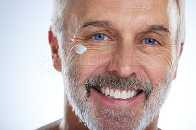 Buy stock photo Old man, cream and smile, eye and wrinkle with skincare, face and beauty, hygiene and grooming on studio background. Portrait, moisturizer and dermatology, anti aging cosmetics and male closeup