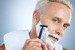 Senior man, face and razor for shaving, skincare or grooming beard and hair removal against a studio background. Portrait of mature male with shaver, cream or foam cosmetics for facial treatment