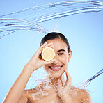 Shower, lemon and water splash with portrait of woman in studio for natural cosmetics, nutrition and detox. Glow, fruits and hydration with female on blue background for vitamin c, face and skincare