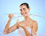 Happy woman, dropper and water splash for skincare serum, product or cream against a blue studio background. Calm female smile holding pipette for beauty cosmetics, essential oil or facial treatment