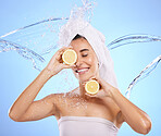 Shower, lemon and water splash with woman in studio for natural cosmetics, nutrition and detox. Glow, fruits and spa hydration with female on blue background for vitamin c, face and skincare