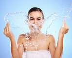 Water splash, portrait or girl with face wash for skincare, fresh body hygiene on blue background in studio. Female model with clean hands or wellness washing in beauty grooming for facial treatment 