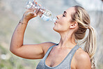 Fitness, woman and drinking water on workout break for hydration, recovery or running exercise in nature. Thirsty active female having natural drink to stay hydrated after intense cardio training