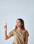 Idea, thinking and a pointing woman with space isolated on a white background in a studio. Direction, mockup and a girl gesturing for a plan, contemplation or a decision on a backdrop or wall