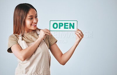 Buy stock photo Coffee shop, small business and woman holding an open sign in studio on a gray background for hospitality. Cafe, startup and management with a female entrepreneur indoor to display advertising