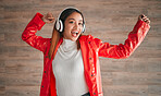 Woman, singing and dancing with music headphones isolated on a wood background. Happiness, dance and portrait of female, person or singer listening, streaming and enjoying audio, radio or podcast.