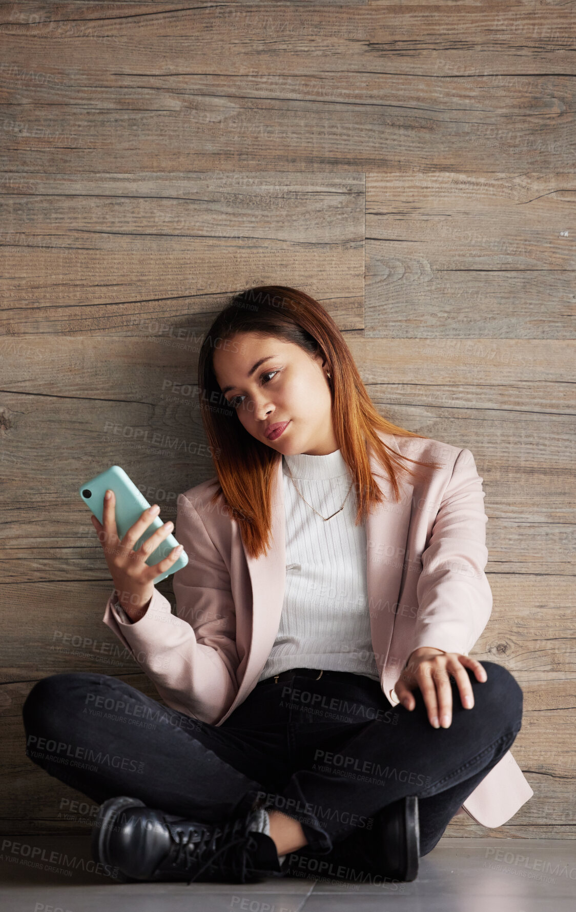 Buy stock photo Young business woman, floor and texting with bored face on social media, app or phone in modern office. Professional female, smartphone and tired with search for email, chat or communication on break