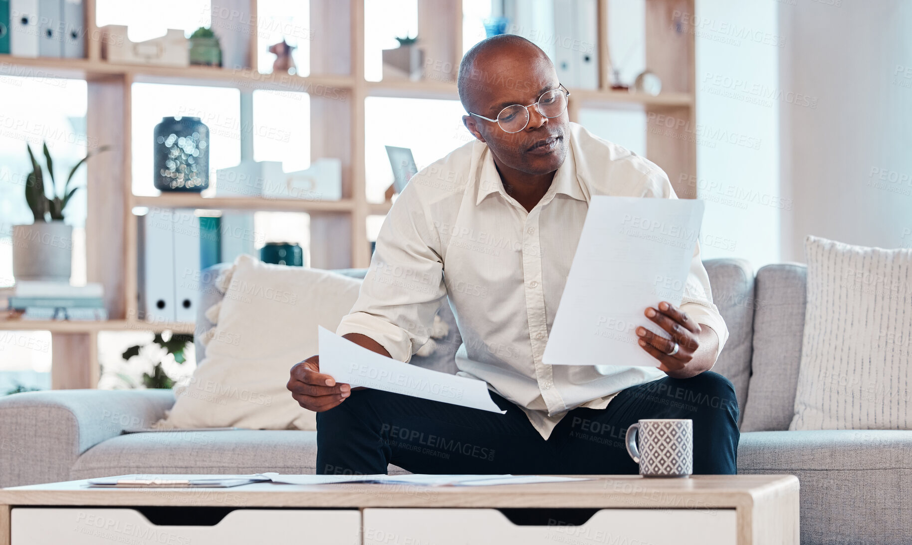 Buy stock photo Man reading paperwork in living room home for planning, budget report and investment contract. Black male, notes and remote work in lounge of tax documents, financial savings or insurance information