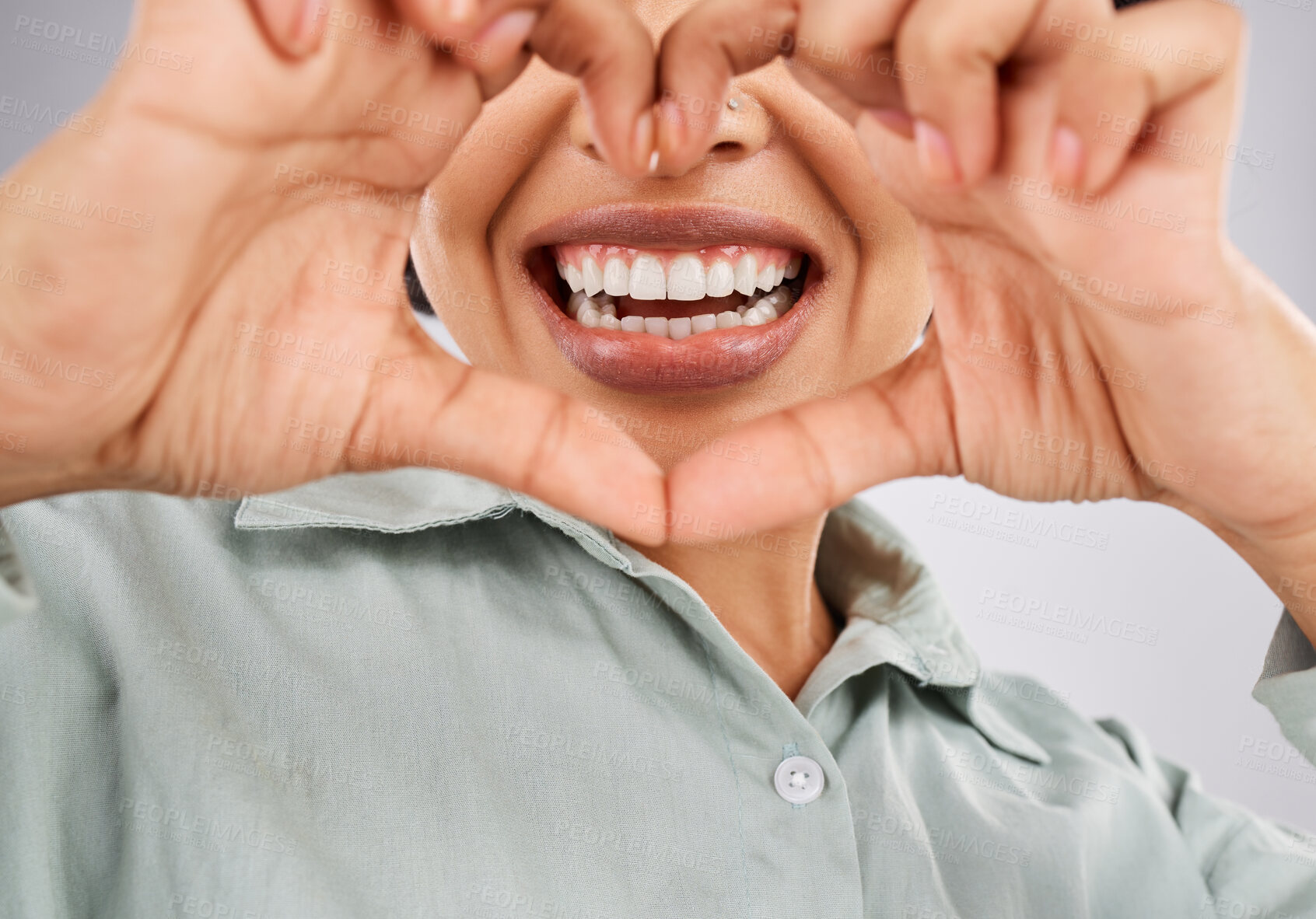 Buy stock photo Love, smile and hands of a black woman with a heart isolated on a studio background. Happy, mouth and closeup of an African girl showing a shape for dental care, oral hygiene and teeth whitening