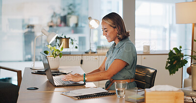 Buy stock photo Woman at desk, happy and typing on laptop for market research, email or social media post at startup. Businesswoman in office with computer, documents and writing article for digital marketing agency