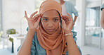 Face, muslim and working with a business woman adjusting her hijab while sitting in the office for work. Hands, head or empowerment with an islamic female employee moving her headscarf in a workplace