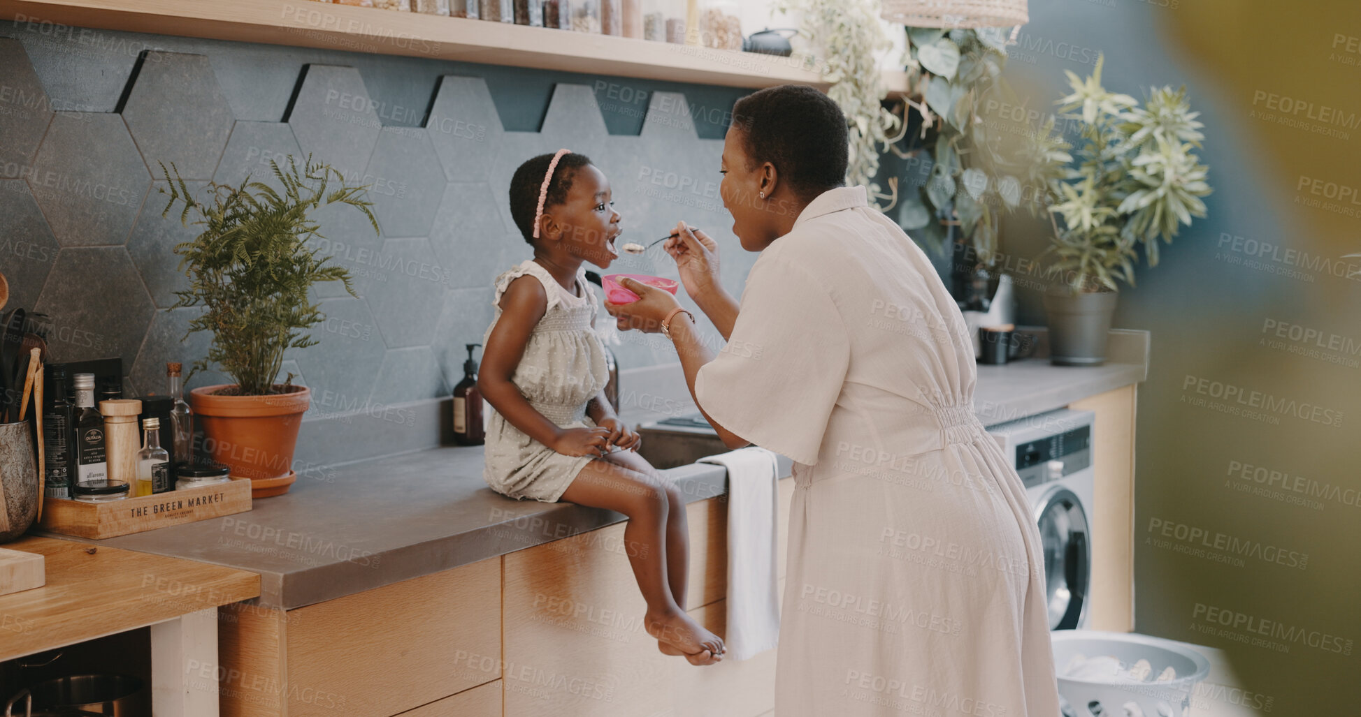 Buy stock photo Black family, breakfast and mother feeding a girl child in the kitchen of their home while together in the morning. Children, food or care and a young daughter with her woman parent in a house