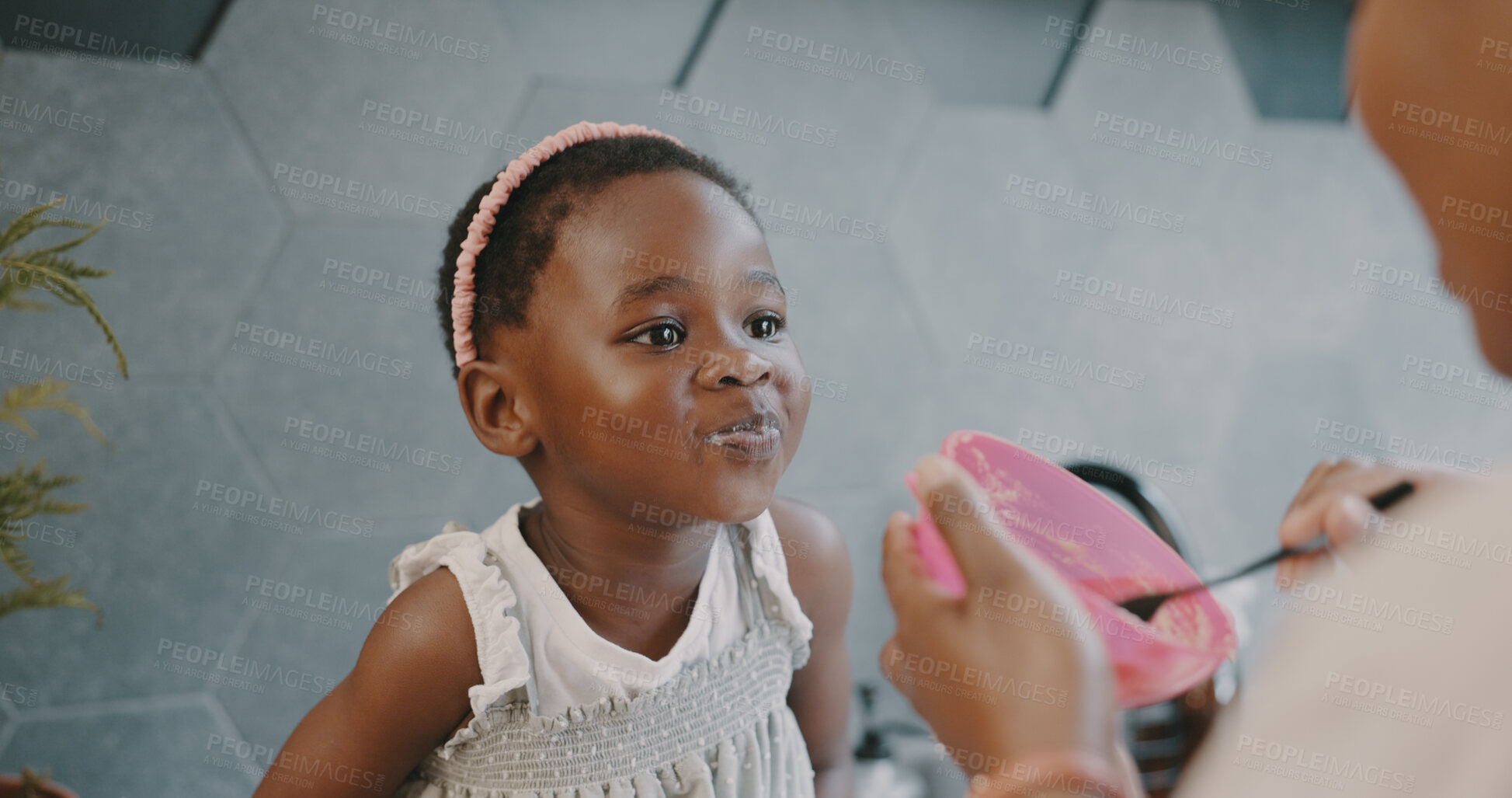 Buy stock photo Black family, breakfast and a parent feeding her daughter in the kitchen of their home while together in the morning. Children, food or care and a little girl eating cereal or porridge in a bowl