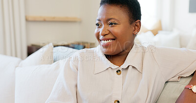 Happy, smile and black woman relaxing on a sofa while watching tv in the living room of her modern house. Happiness, laughing and African lady streaming a movie while sitting on a couch in her lounge
