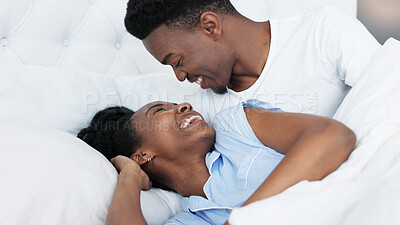 Happy black couple in bedroom kiss and smile for love, romance and intimacy at house or home in morning. Young, happiness and kissing black woman and man or romantic black people dating bond together