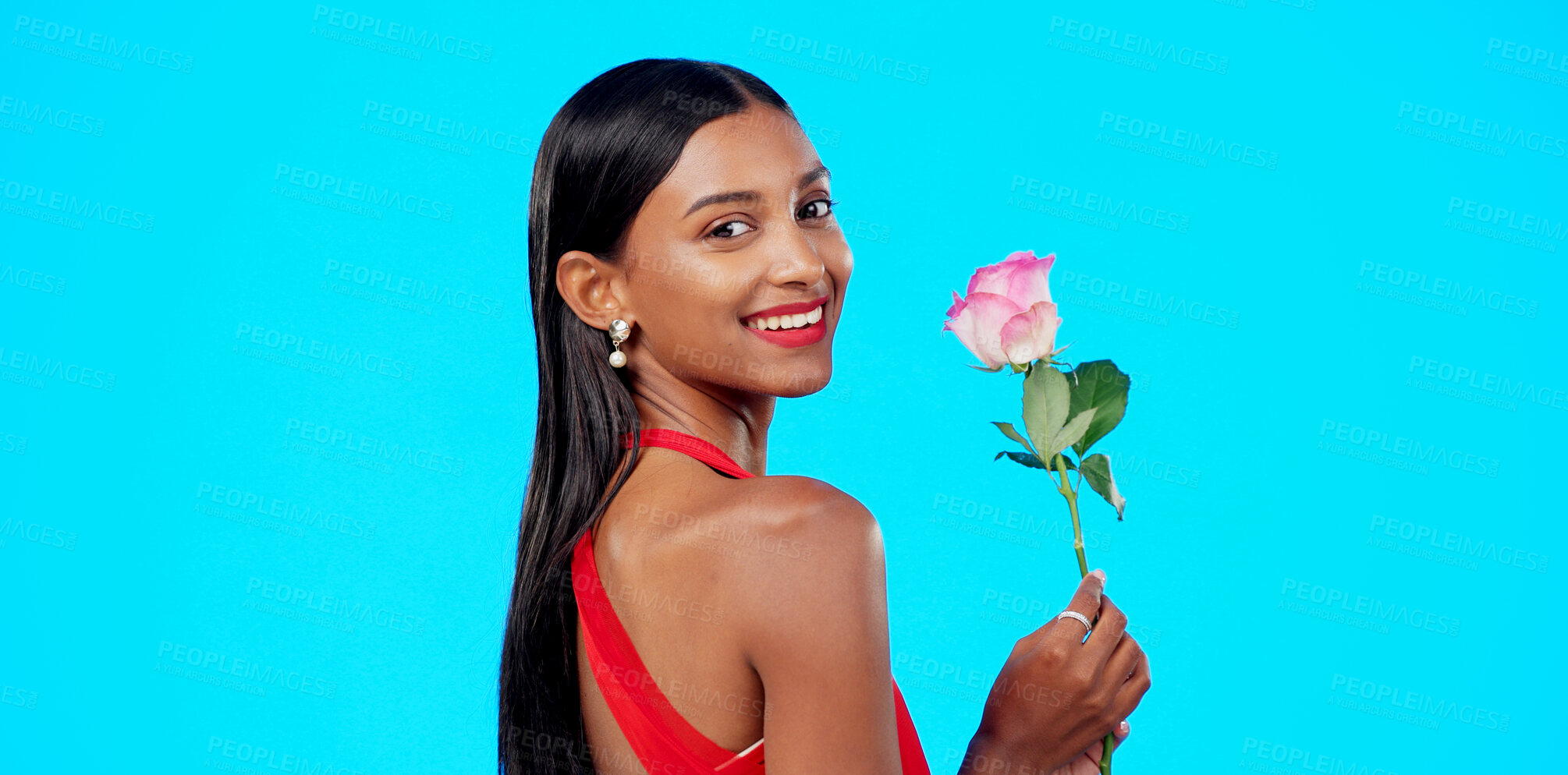 Buy stock photo Rose, smile and portrait of young woman in a studio for valentines day or anniversary gift. Happy, romance and Indian female model with flower for love present isolated by a blue background.