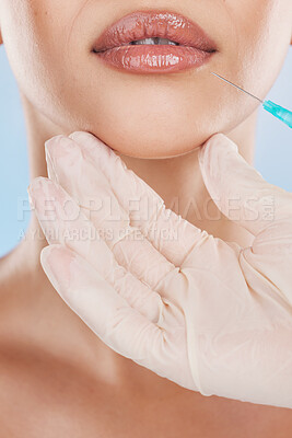 Buy stock photo Needle, surgery and lips with a woman getting an injection in her mouth for beauty, skincare and medicine in studio on a blue background. Filler, product and cosmetics with a young female model inside