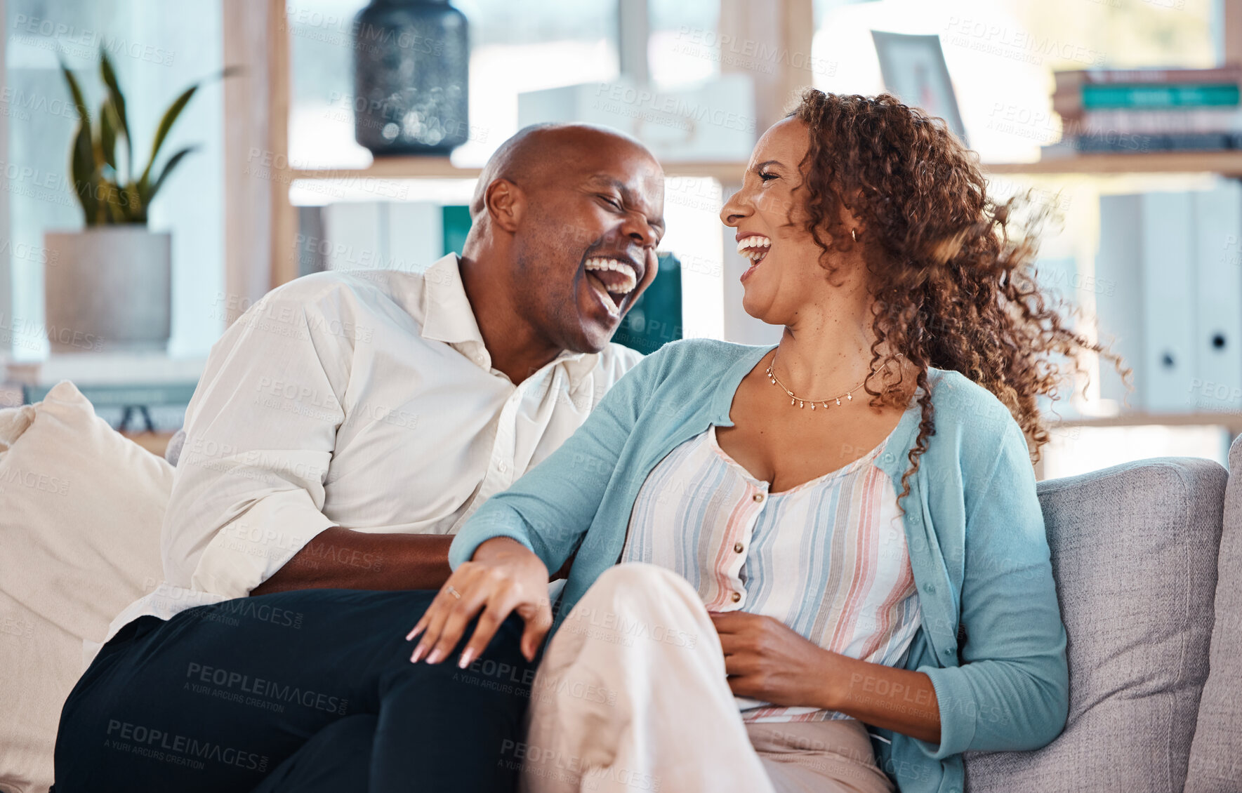 Buy stock photo Love, happy and couple laugh on sofa for bonding, quality time and relaxing together at home. Marriage, interracial relationship and man and woman on couch embrace, hugging and laughing at funny joke