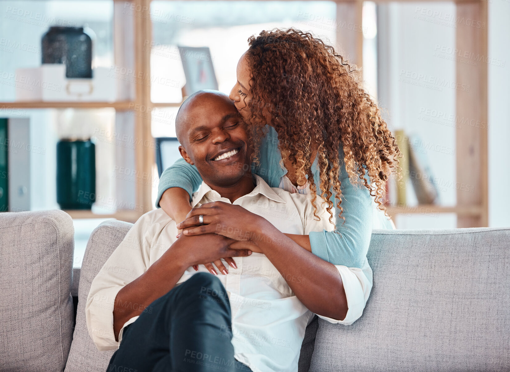 Buy stock photo Love, happy and couple kiss on sofa for bonding, quality time and relaxing together at home. Marriage, interracial relationship and man and woman on couch embrace, hugging and laughing in living room