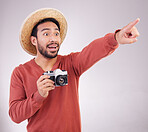 Travel, camera and shocked man pointing on holiday, adventure and mockup on white background. Smile, travel and happy person in studio showing gesture of shock on vacation with discovery on journey.