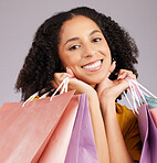 Happy woman, face and portrait smile with shopping bags for discount, sale or fashion against gray studio background. Female shopper smiling and holding gifts or shop accessories posing in happiness