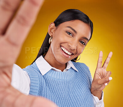 Buy stock photo Selfie, peace sign and portrait of Indian woman in studio for happiness, confident and smile on yellow background. Emoji mockup, fashion and girl with hand gesture with beauty, cosmetics and style