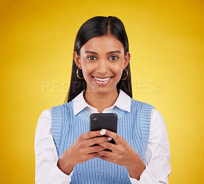 Buy stock photo Smile, phone and portrait of woman in studio space typing message or email on yellow background. Technology, communication and happy face of Indian gen z model checking social media or online content