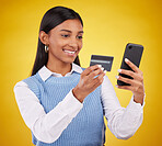 Smile, phone and credit card, woman in studio for ecommerce or online shopping payment on yellow background. Technology, communication and mobile app happy girl checking internet banking and budget.