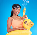 Portrait, bubbles and rubber duck with a woman on a blue background in studio ready for summer swimming. Happy, vacation and goggles with an attractive young female looking excited to relax or swim