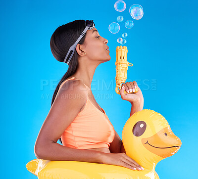 Buy stock photo Bubbles, goggles and rubber duck with a woman on a blue background in studio ready for summer swimming. Happy, travel and vacation with an attractive or playful young female blowing a bubble gun