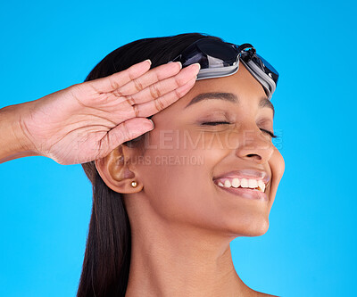 Buy stock photo Face, smile and salute with a swimmer woman in studio on. a blue background wearing goggles on her head. Happy, hand gesture and swimming with an attractive young female excited to swim in summer