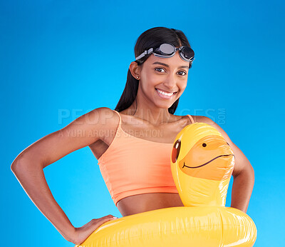Buy stock photo Portrait, goggles and rubber duck with a woman on a blue background in studio ready for summer swimming. Happy, vacation or hands on hips with an attractive young female looking excited for a swim