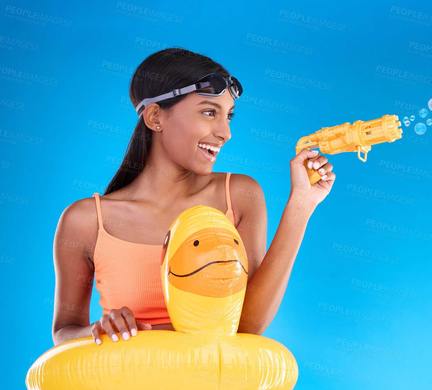 Buy stock photo Bubbles, summer swimsuit and woman with bubble gun in a studio with fun and happiness. Isolated, blue background and happy female model with playful smile and swimming outfit for pool entertainment