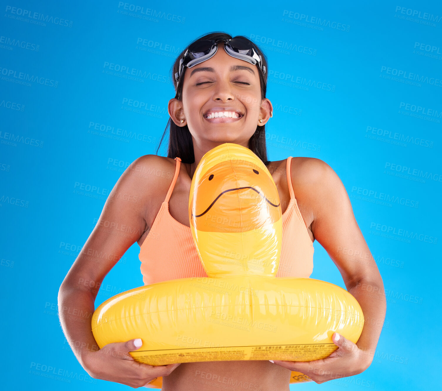 Buy stock photo Smile, goggles and rubber duck with a woman on a blue background in studio ready for summer swimming. Happy, travel and vacation with an attractive young female feeling excited to relax or swim