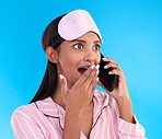 Phone call, surprise and female in pyjamas in a studio with shocking, winning or good news. Communication, shock and woman model on a mobile conversation with wtf, omg or wow face by blue background.