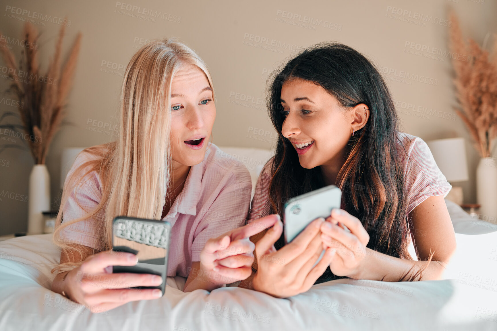 Buy stock photo Wow, happy and women with a phone on a bed for social media, communication and notification. Shock, smile and friends reading news, message or online chat on a mobile during a sleepover together