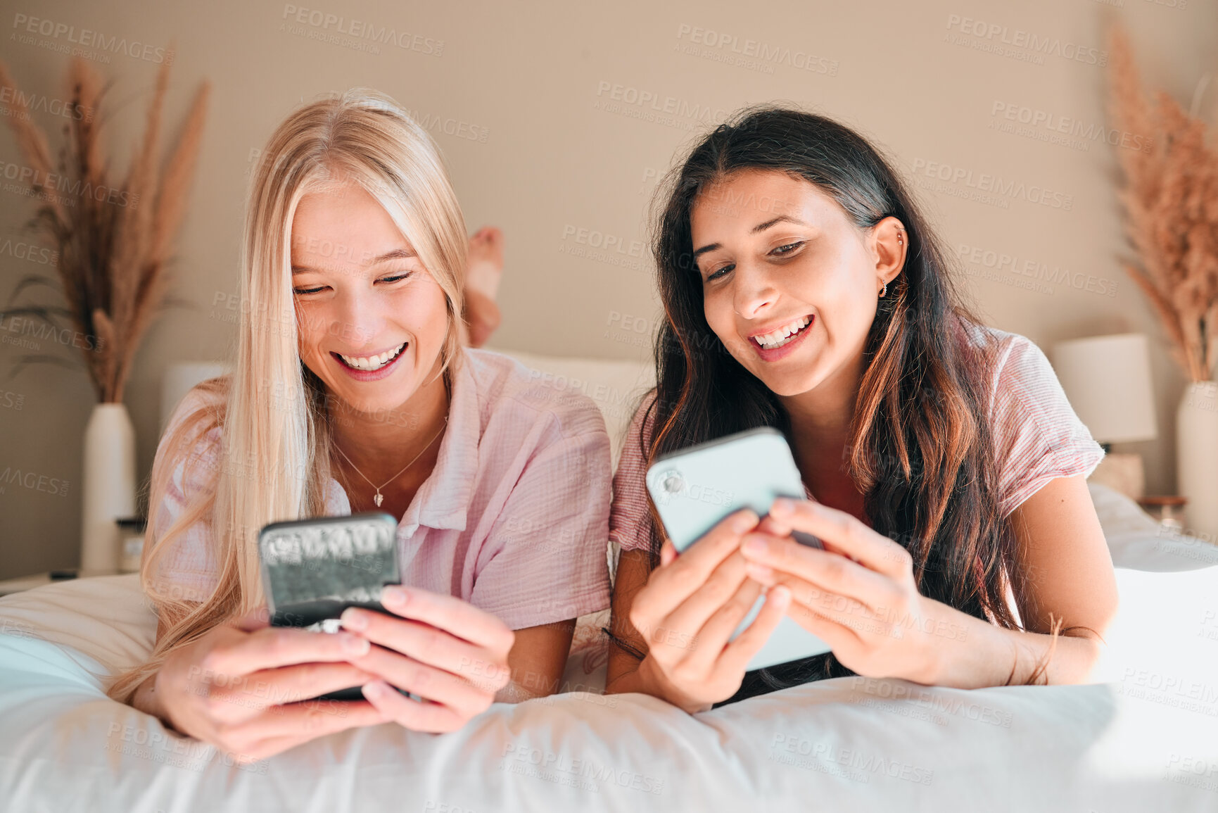 Buy stock photo Teen friends, smartphone and girl on bed, relax and smile on face, social media scroll and happiness at home. Technology, young people chat on internet with gen z and phone app with meme online