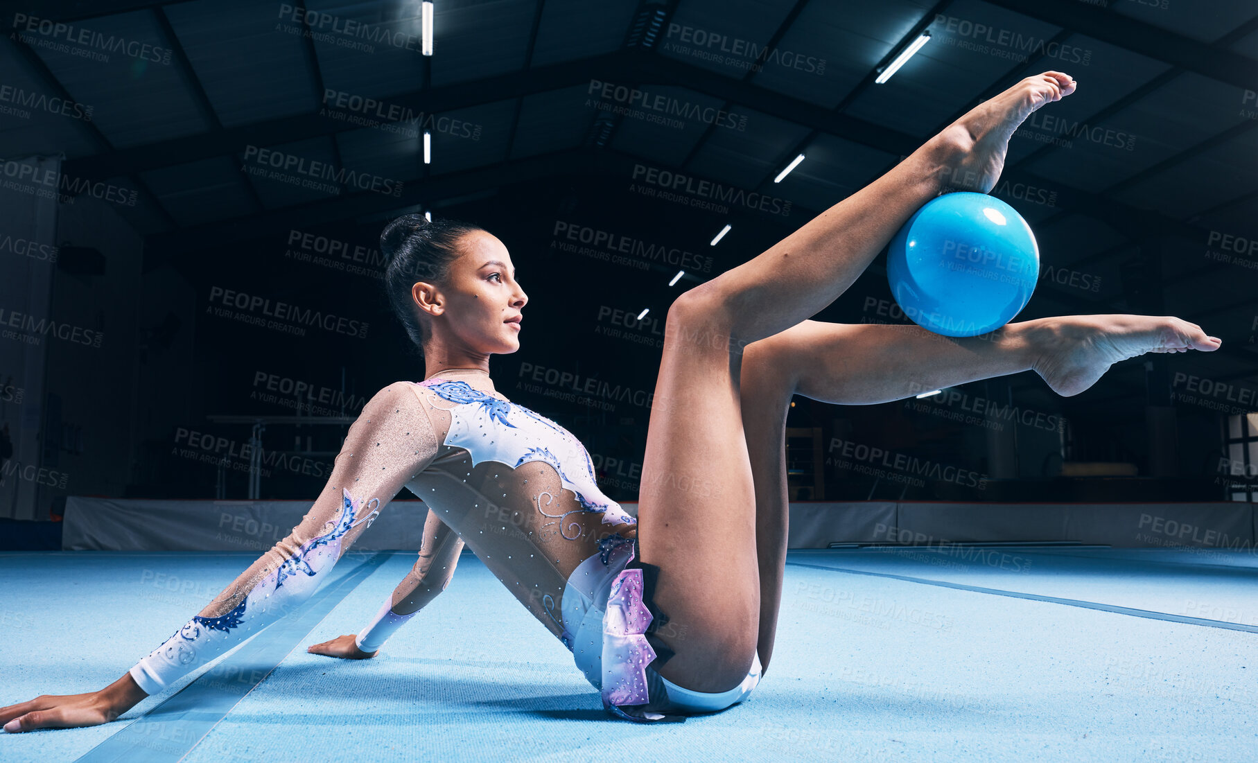 Buy stock photo Woman, gymnastics and ball between legs of performance, competition training or dancing in dark sports arena. Female athlete, rhythmic movement and creative talent in solo concert, agility or balance