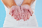 Water, washing and splash with hands of woman in studio for beauty, sustainability and skincare. Shower, cleaning and cosmetics with female in blue background for self care, spa and disinfection